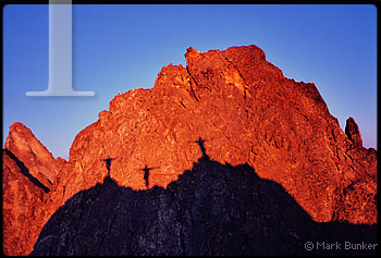 Silhouette of 3 climbers at sunset, at the "blob bivy" on the Picket Traverse.